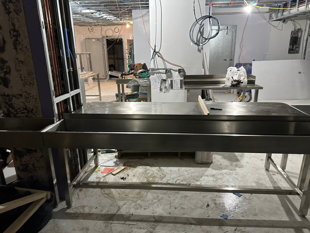 Assembling the stainless counters, with the walk-in doors already in place in the back. We moved the electrical panel to the bathroom. The old panel spot on the right is now the dishwasher area.